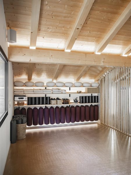 Salle de yoga avec matériel rangé sur étagères